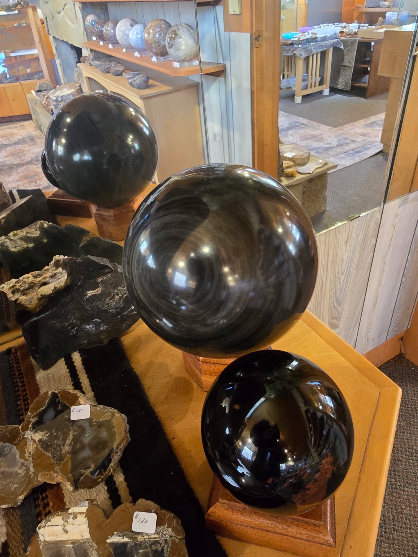 Large polished obsidian spheres on wooden bases